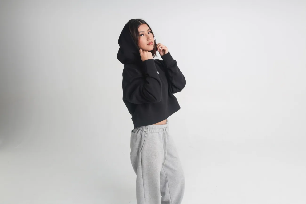 Studio fashion model wearing a black hoodie and grey trousers